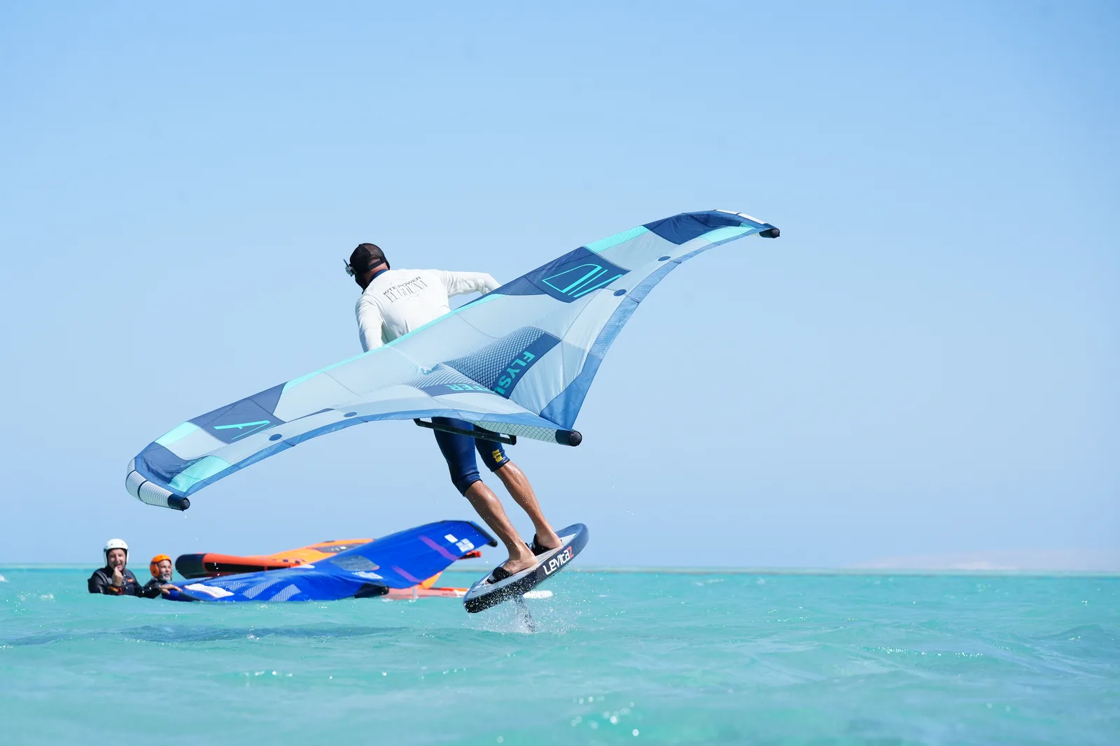 Kitefoilista jedoucí nad rovnou tyrkysovou vodou laguny v El Gouně na hydrofoilu
