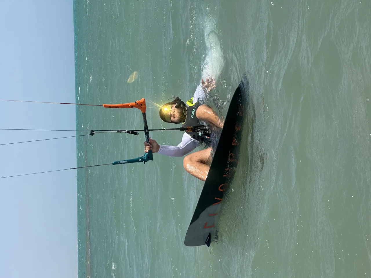 Kitesurfař vykrajuje oblouk na hladině laguny