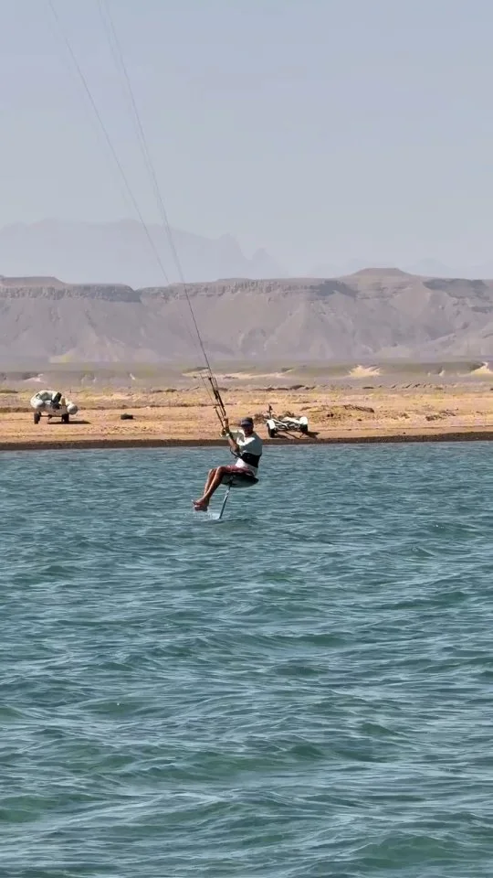 Kitefoiler při krátkém kontrolovaném letu nad rovnou vodou laguny