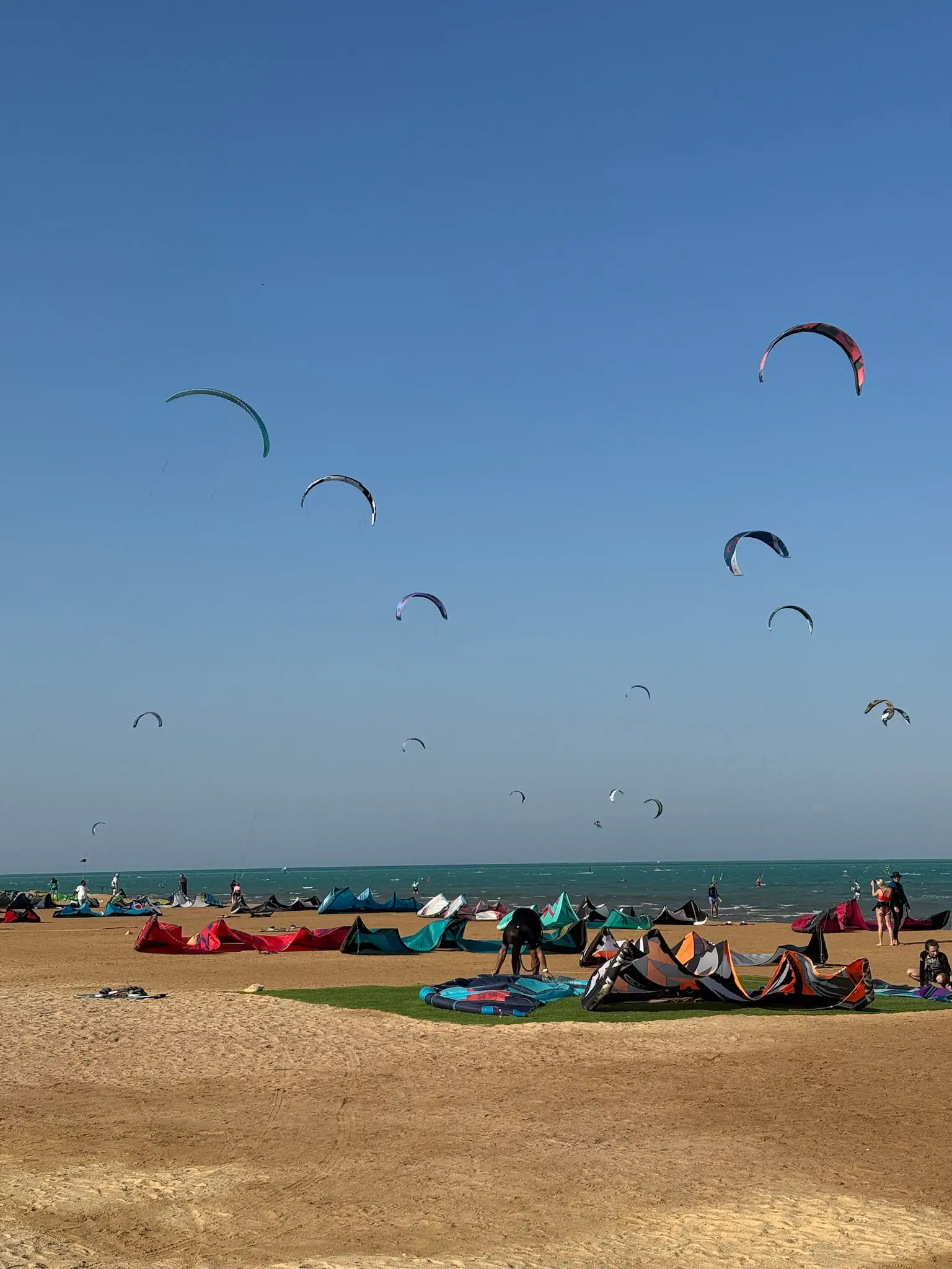 Kity létající nad tyrkysovou lagunou s rovnou vodou na pláži Kitepower El Gouna