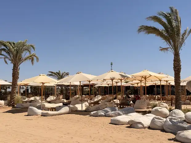 Řady krémových slunečníků a sedacích vaků na písku v beach clubu SALT v El Gouně